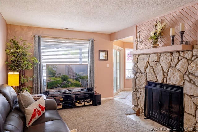 carpeted living room featuring a textured ceiling and a stone fireplace