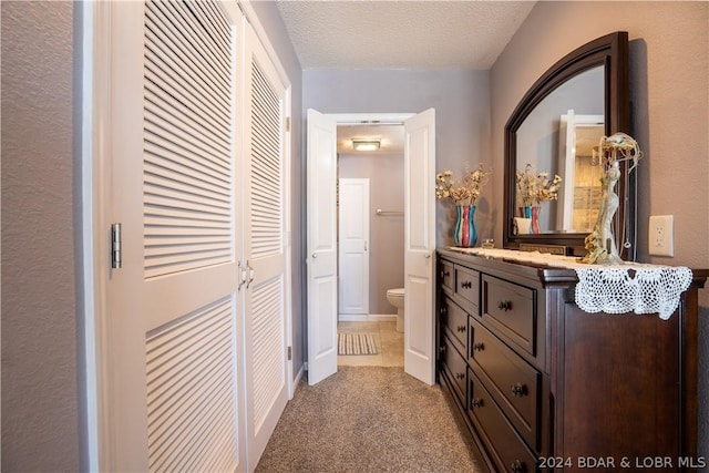 corridor featuring a textured ceiling and light carpet