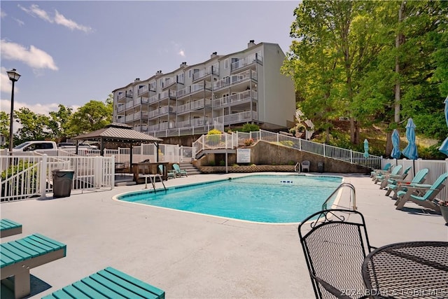 pool with a gazebo, a patio, and fence