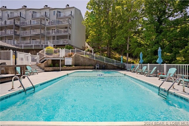 community pool with a patio and fence