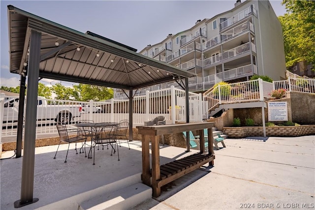 surrounding community featuring a gazebo, a patio area, outdoor dining space, and fence