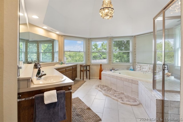 bathroom with a wealth of natural light, vanity, tile floors, and tiled bath