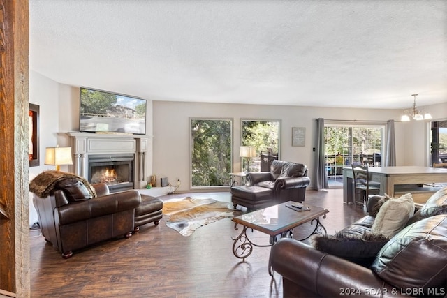 living room featuring a textured ceiling, dark wood-type flooring, and a notable chandelier