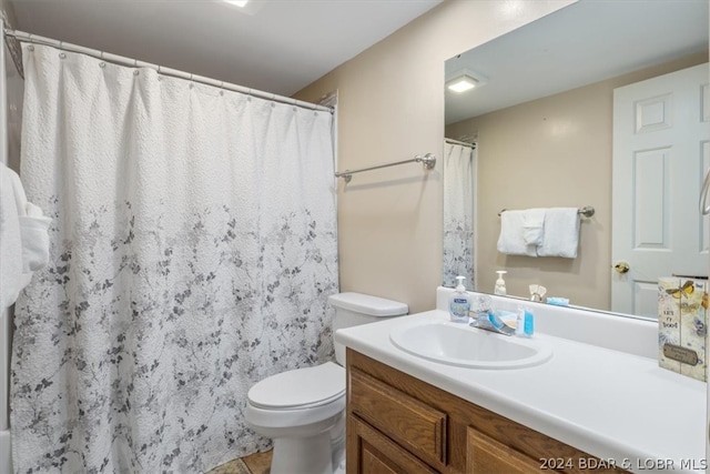 bathroom featuring tile flooring, vanity, and toilet