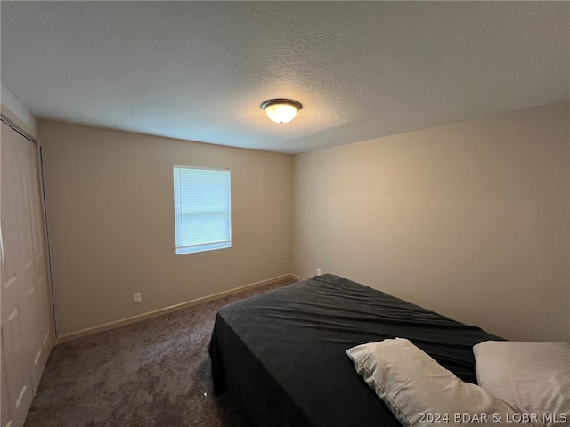 carpeted bedroom with a closet and a textured ceiling