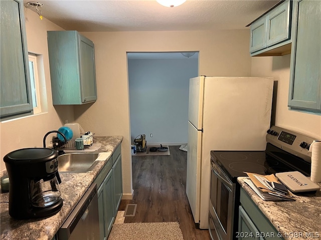 kitchen featuring dark wood-type flooring, green cabinets, stainless steel appliances, stone counters, and sink