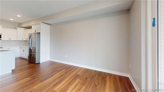 kitchen with white cabinetry, hardwood / wood-style floors, and stainless steel fridge