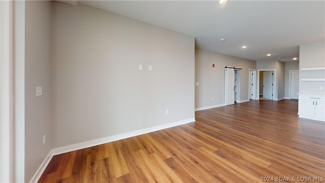 empty room with light wood-type flooring and a barn door