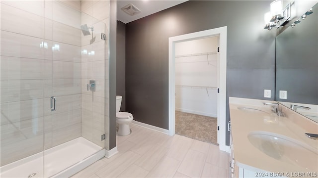 bathroom featuring toilet, a shower with door, and vanity