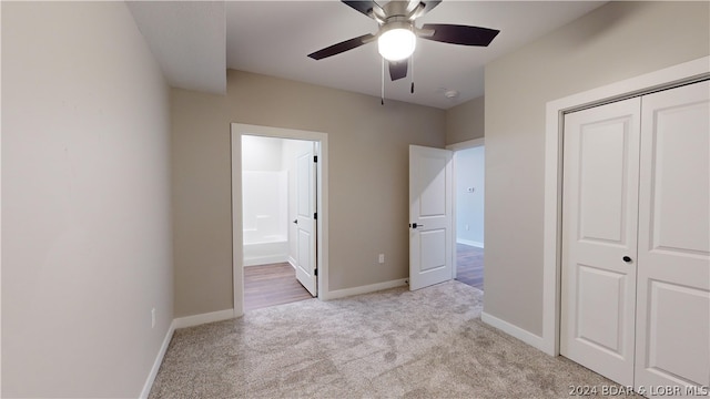 unfurnished bedroom featuring ceiling fan, ensuite bath, a closet, and light carpet