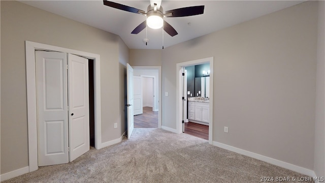 unfurnished bedroom with ensuite bath, a closet, ceiling fan, and light colored carpet