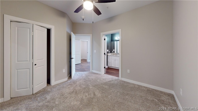 unfurnished bedroom with ceiling fan, light colored carpet, a closet, and ensuite bath