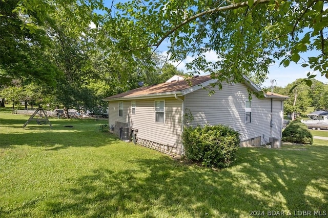 view of side of property featuring central AC and a lawn