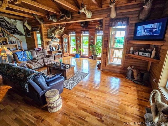 living room featuring hardwood / wood-style floors, lofted ceiling with beams, and rustic walls