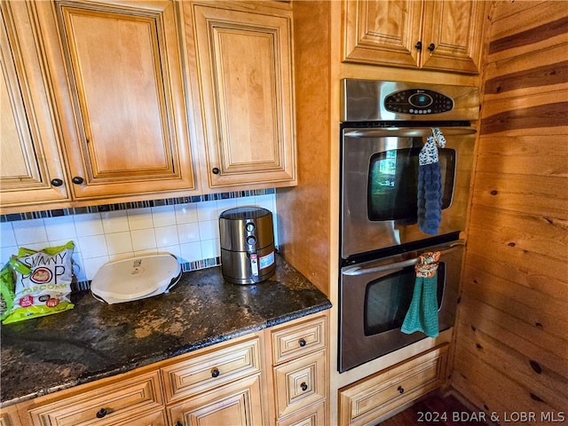 kitchen with dark stone countertops, tasteful backsplash, and stainless steel double oven