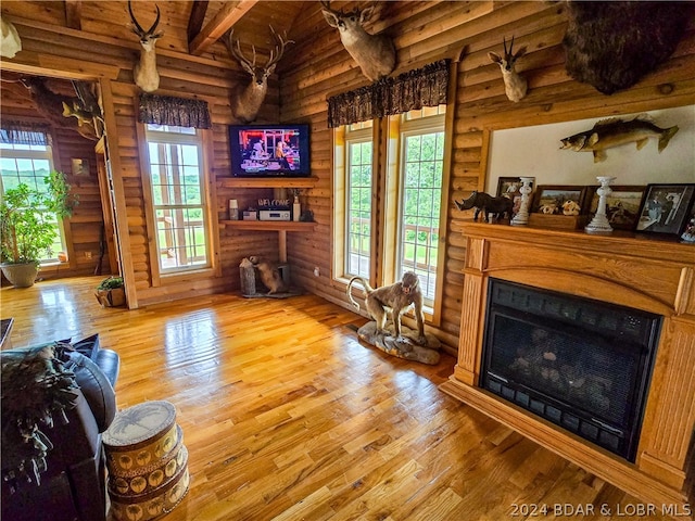 living room featuring beam ceiling, rustic walls, and wood-type flooring