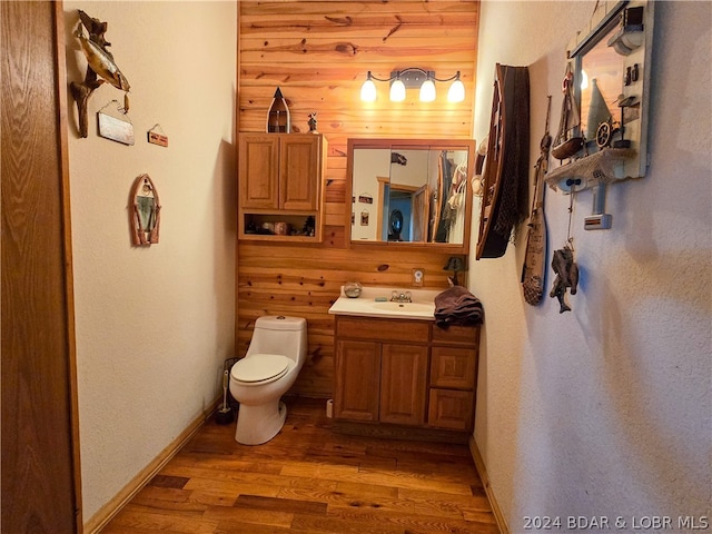 bathroom featuring vanity, toilet, wood walls, and hardwood / wood-style floors