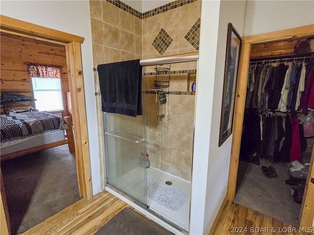 bathroom with a shower with shower door and hardwood / wood-style floors