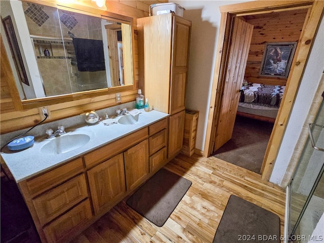 bathroom featuring vanity, wood walls, wood-type flooring, and an enclosed shower