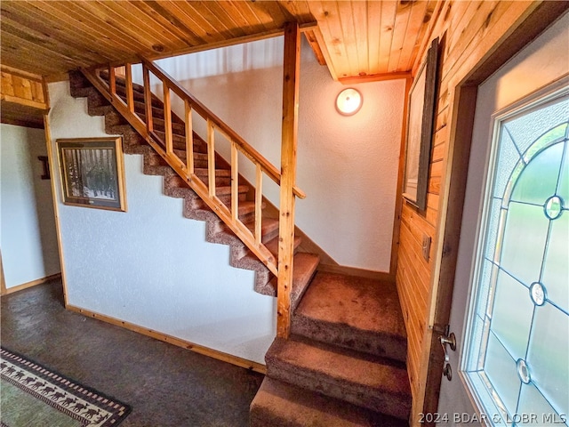 staircase with wooden ceiling, carpet floors, and wooden walls