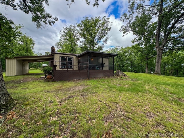 back of property with a yard, a carport, and a sunroom