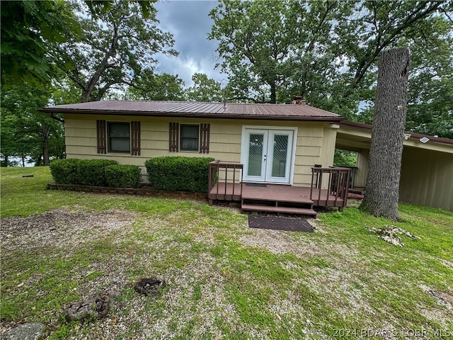 view of front of home featuring a deck, a front yard, and french doors