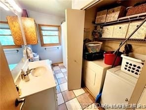 washroom with washing machine and clothes dryer, sink, and light tile patterned floors