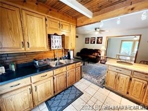 kitchen featuring light tile patterned flooring, sink, ceiling fan, beam ceiling, and wood ceiling