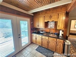 kitchen with french doors, wood ceiling, sink, beamed ceiling, and light tile patterned flooring