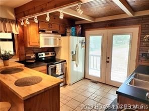 kitchen featuring white appliances, french doors, sink, light tile patterned flooring, and kitchen peninsula