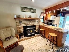 kitchen featuring a breakfast bar, white appliances, kitchen peninsula, and light tile patterned floors