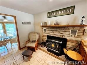 sitting room featuring ceiling fan, a fireplace, and light tile patterned floors