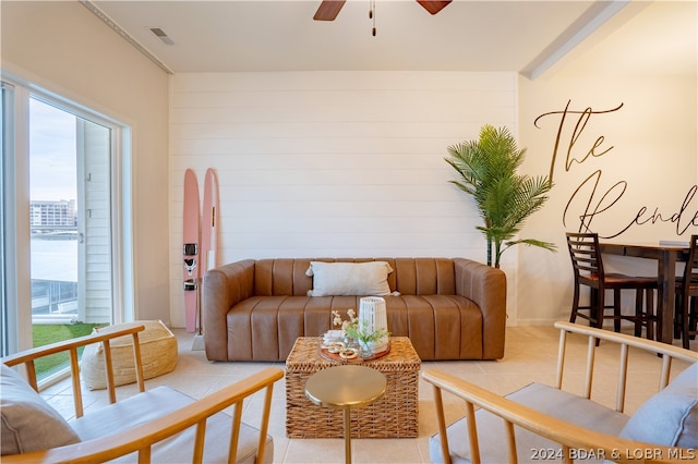 tiled living room featuring ceiling fan and wooden walls