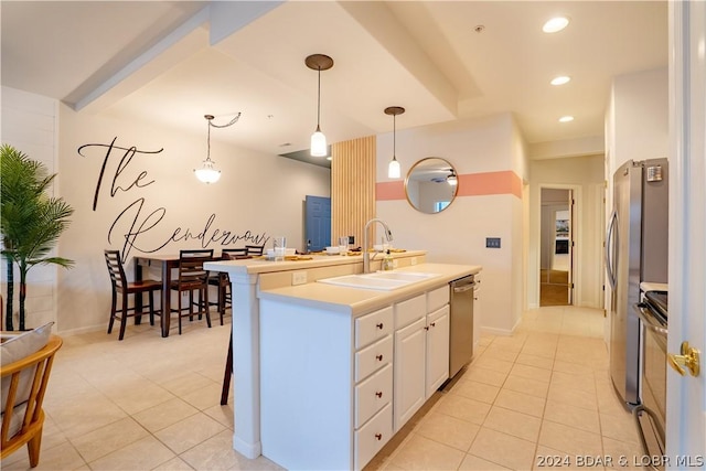 kitchen featuring stainless steel appliances, a kitchen island with sink, sink, pendant lighting, and white cabinets