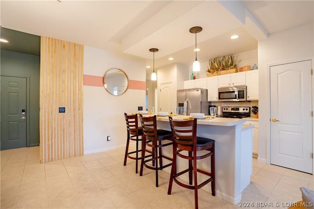 kitchen with hanging light fixtures, stainless steel appliances, tasteful backsplash, an island with sink, and white cabinets