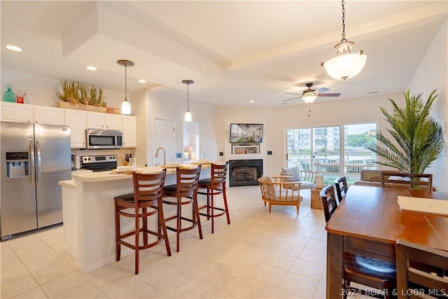 kitchen featuring a kitchen island with sink, hanging light fixtures, ceiling fan, and stainless steel appliances