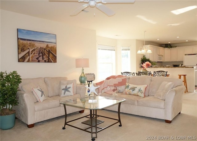 carpeted living room with ceiling fan with notable chandelier