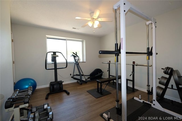 exercise area featuring baseboards, ceiling fan, wood finished floors, and visible vents