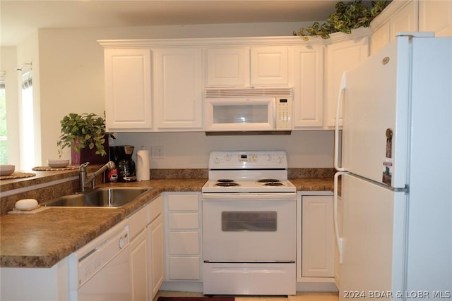kitchen with dark countertops, a sink, white appliances, white cabinetry, and a peninsula