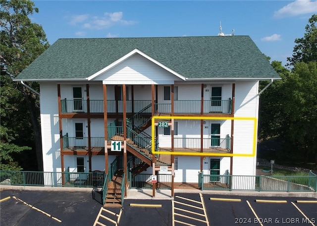 view of building exterior featuring stairs, uncovered parking, and fence