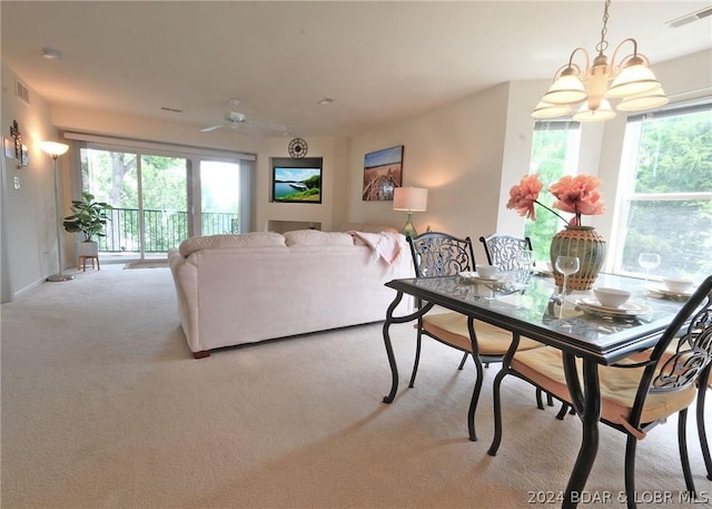 carpeted living room featuring plenty of natural light and ceiling fan with notable chandelier