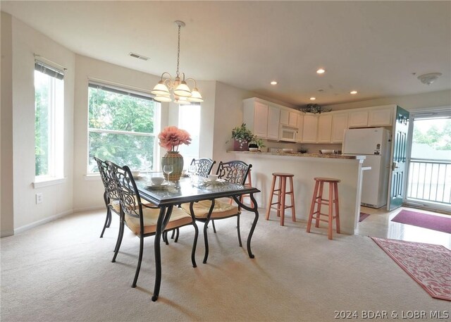 dining room featuring a notable chandelier, light carpet, and a wealth of natural light