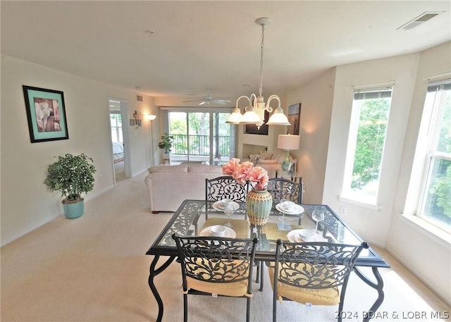 dining space featuring light colored carpet and ceiling fan with notable chandelier