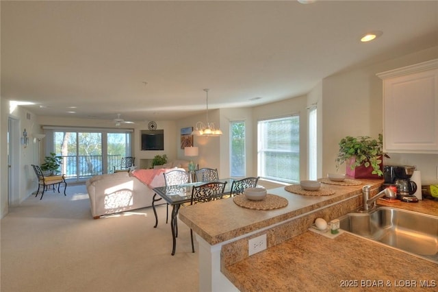 kitchen with white cabinets, light colored carpet, a sink, light countertops, and a peninsula