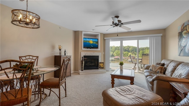 carpeted living room featuring ceiling fan with notable chandelier and a high end fireplace