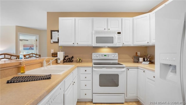 kitchen with sink, white appliances, and white cabinetry