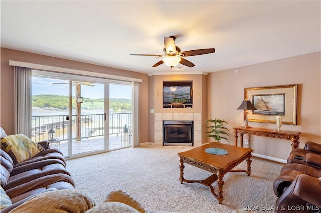 living room featuring a fireplace, a water view, ceiling fan, and light colored carpet