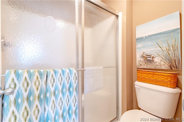 bathroom featuring toilet and a shower with shower door