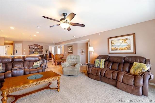 living room with ceiling fan, sink, and light carpet