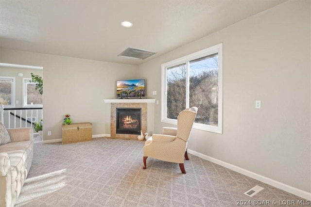 sitting room with a tile fireplace and light carpet